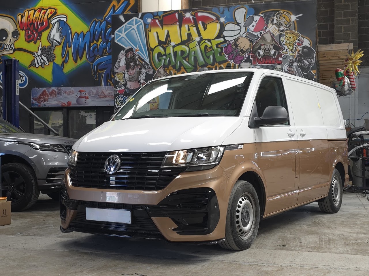 Two-tone Volkswagen Transporter inside Mad Garage, in front of our graffiti wall